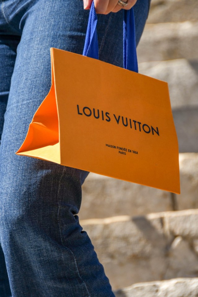 Person carrying a Louis Vuitton shopping bag.