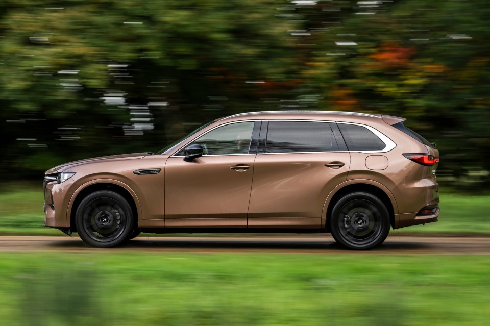 A bronze SUV driving on a road.