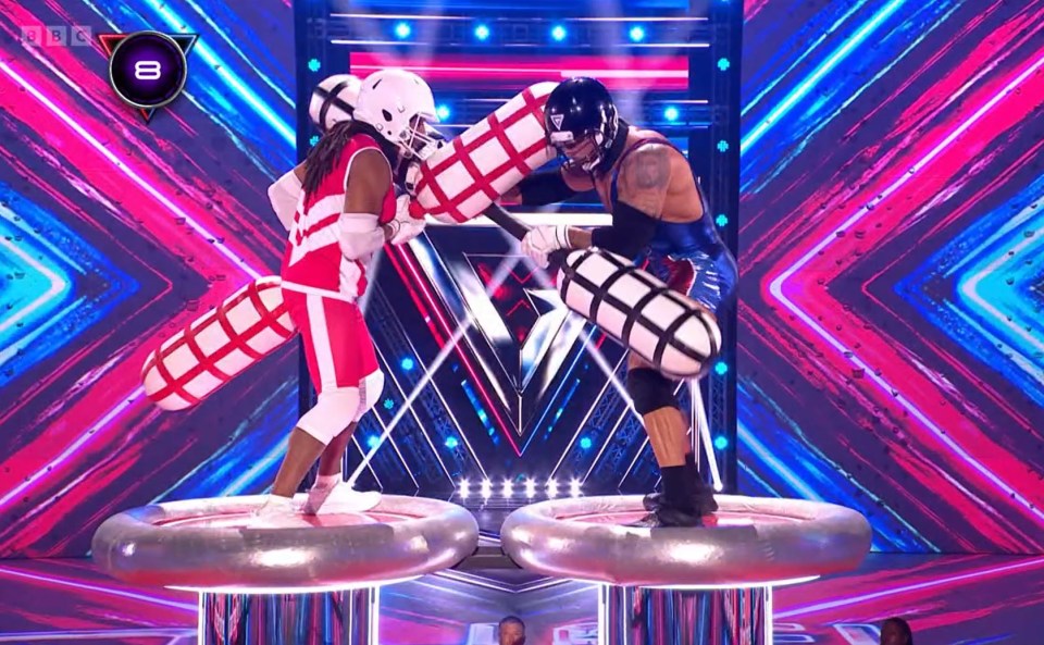 Two contestants on BBC Gladiators compete in a grab-style event.