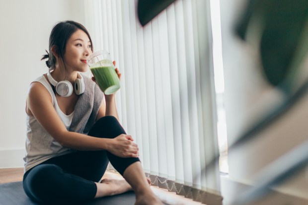 Young woman in sportswear drinks a green smoothie after a workout.