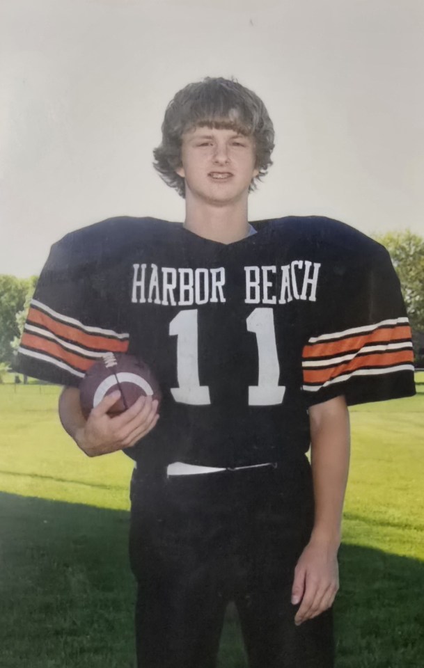 Young man in Harbor Beach football uniform holding a football.