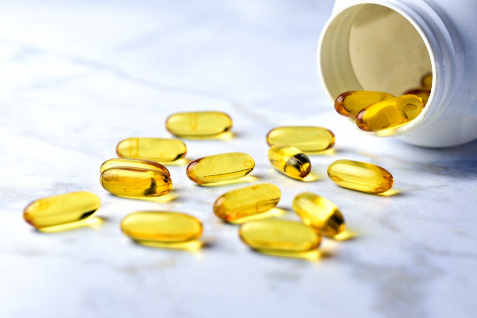 Yellow fish oil pills spilling from a bottle.