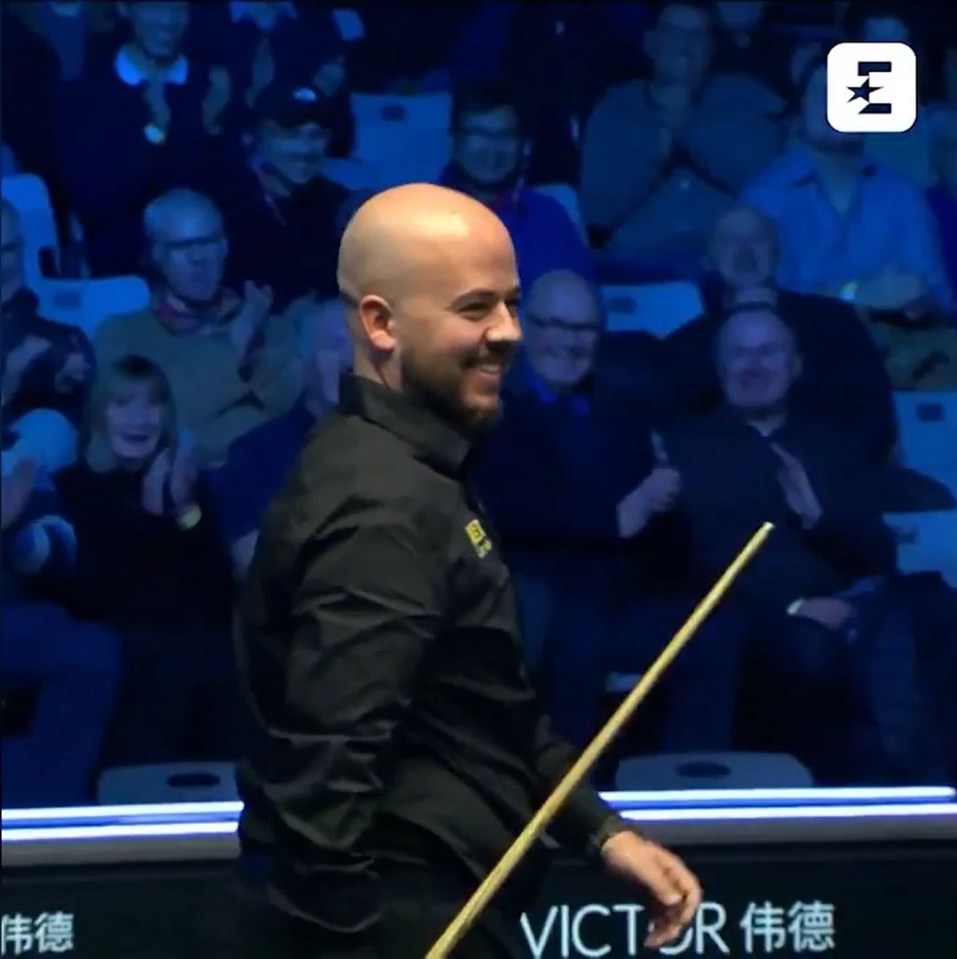 Smiling snooker player holding his cue.