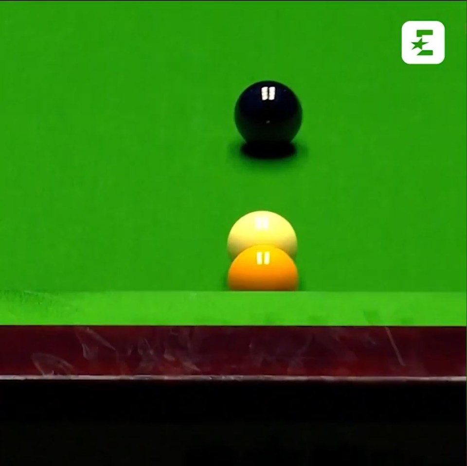 Snooker balls on a green table.  The black ball is at the top, and the yellow and orange balls are touching each other at the bottom.