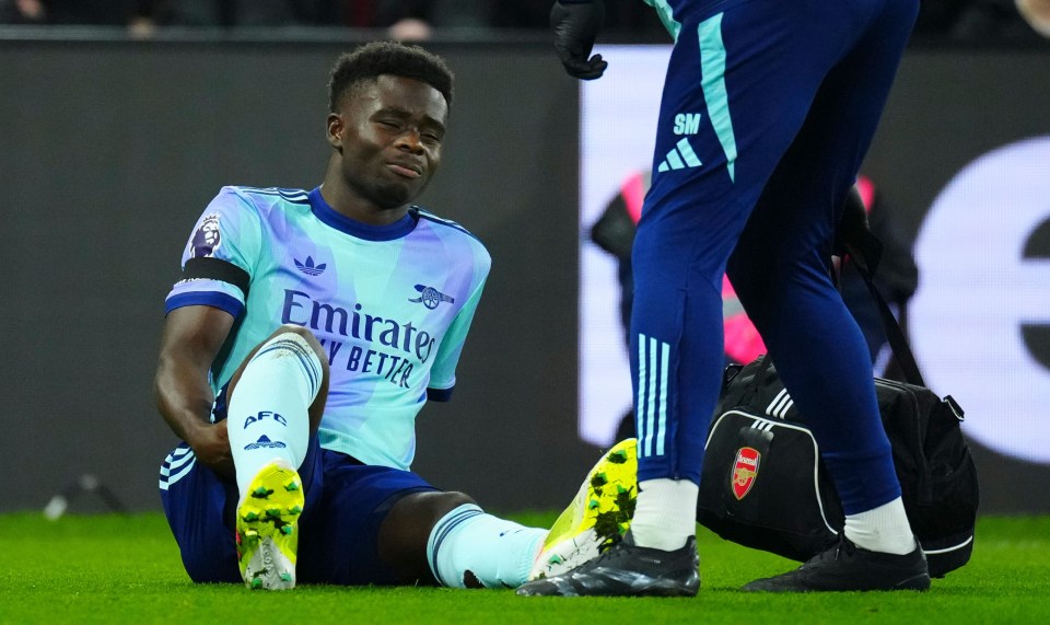 Bukayo Saka of Arsenal clutching his hamstring after an injury.