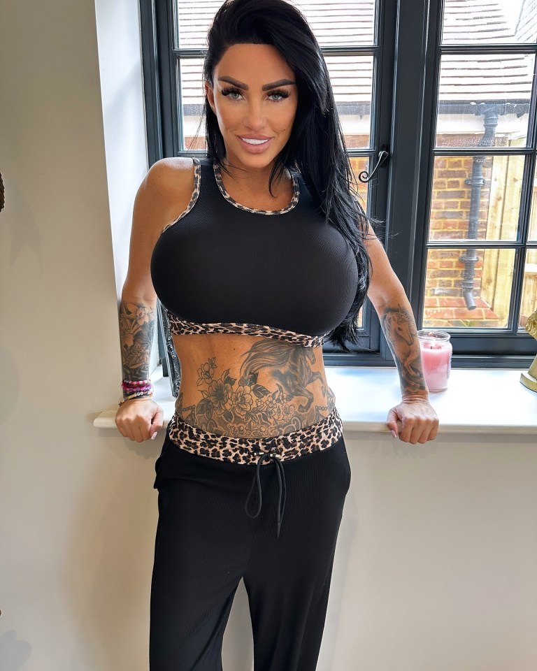 Katie Price in a black crop top and matching pants, showcasing tattoos.