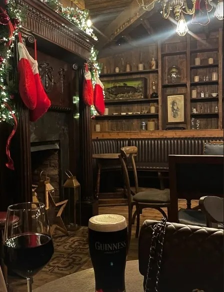 Maura Higgins' Christmas getaway: a cozy pub with a fireplace, Christmas stockings, and drinks.