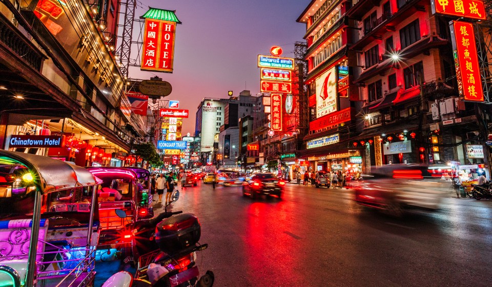 Night view of Chinatown street scene with vibrant neon signs and traffic.