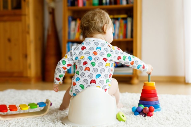 Toddler sitting on potty, playing with toys.