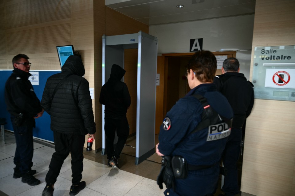 Co-defendants walk through the security portal as they arrive at the Avignon courthouse early December