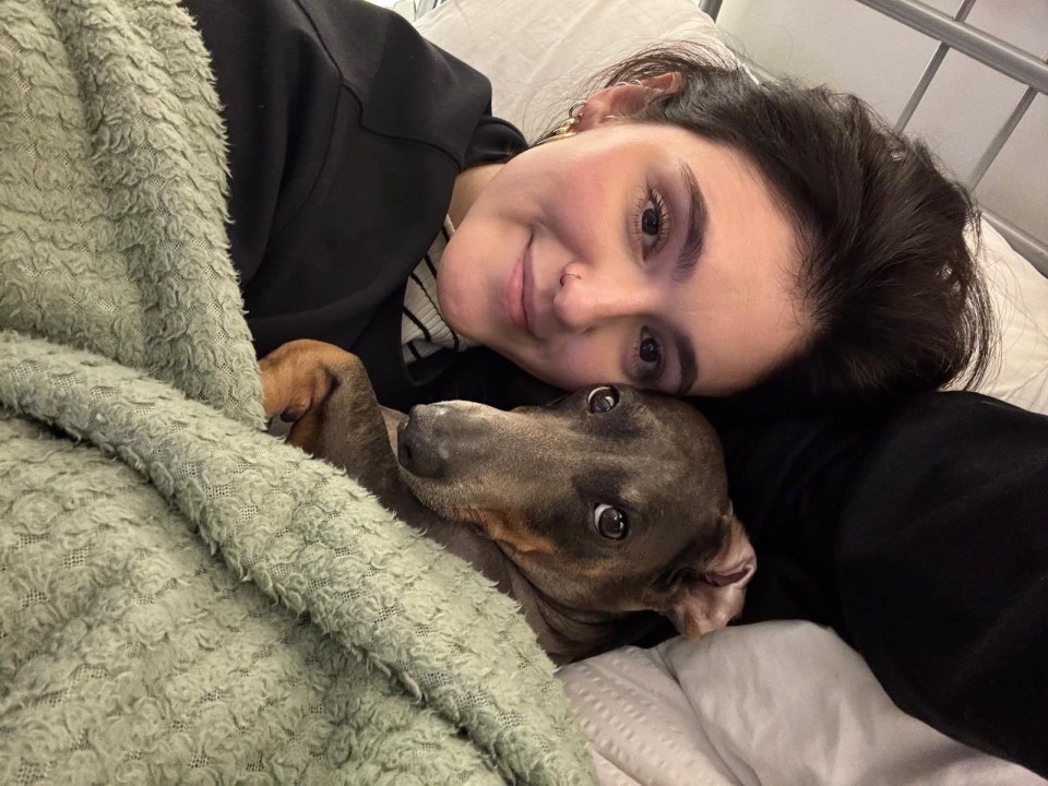 Woman cuddling with her dog under a blanket.