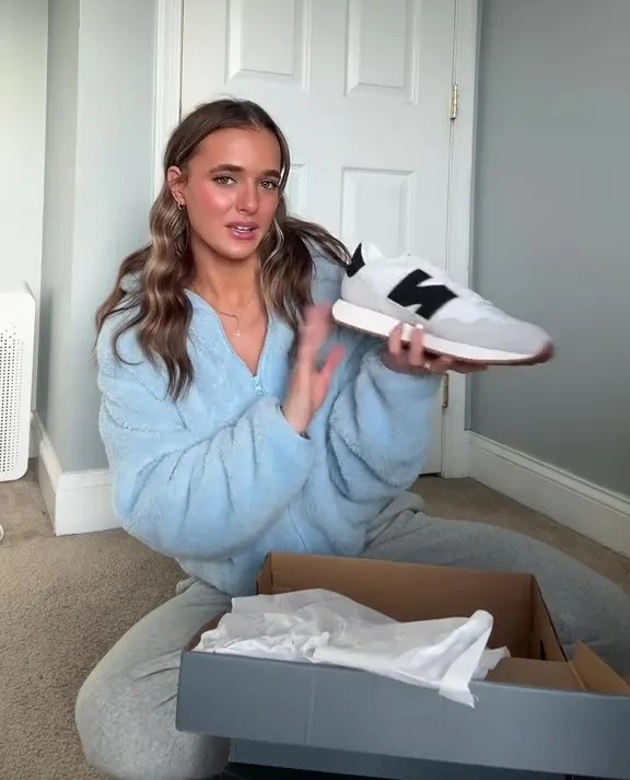 Woman showing off a new pair of shoes she bought for her boyfriend.