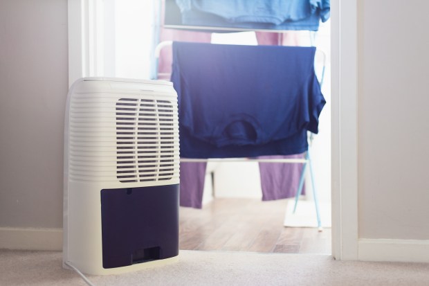 Dehumidifier next to clothes drying rack with laundry.