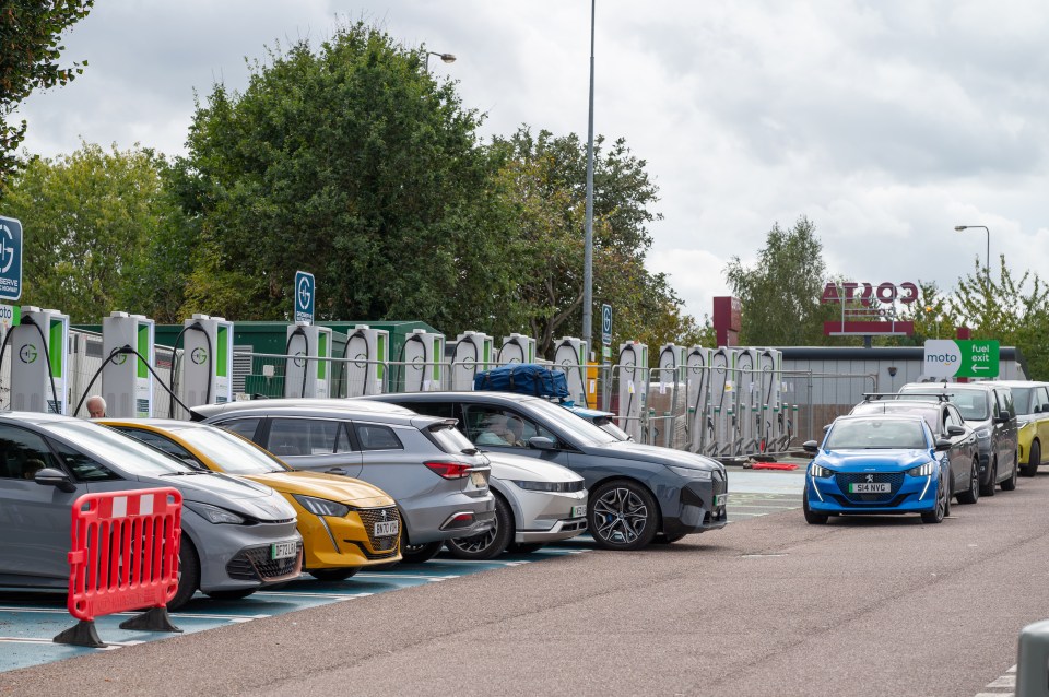 Electric vehicles queuing at a motorway service station charging point.