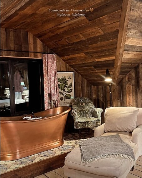 Maura Higgins's countryside Christmas getaway: copper bathtub, armchair, and ottoman in a rustic room.