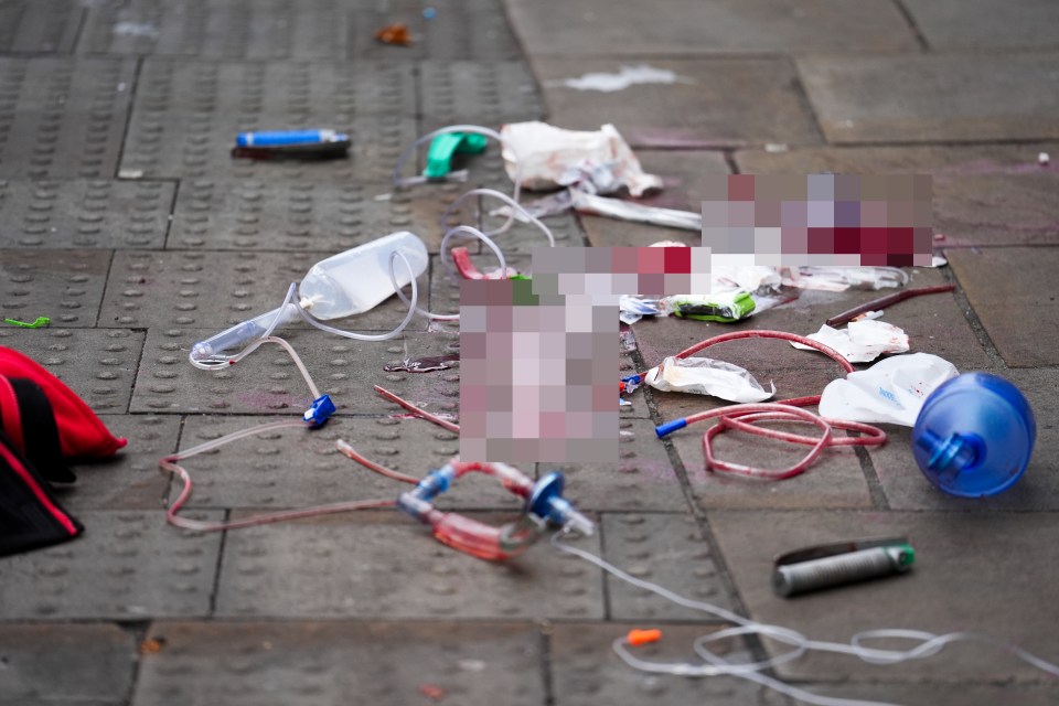 Bloody medical equipment and debris on a pavement following a car attack.