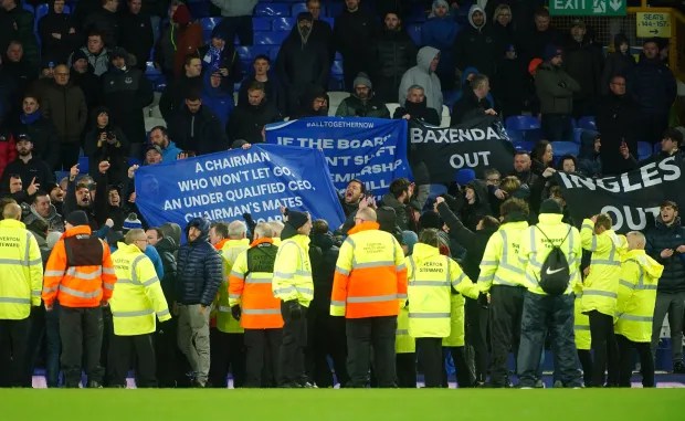 Everton fans protest, holding banners demanding board and chairman changes.