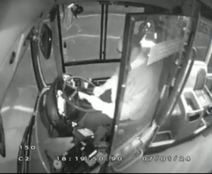 CCTV footage of a bus driver and the road ahead at night.