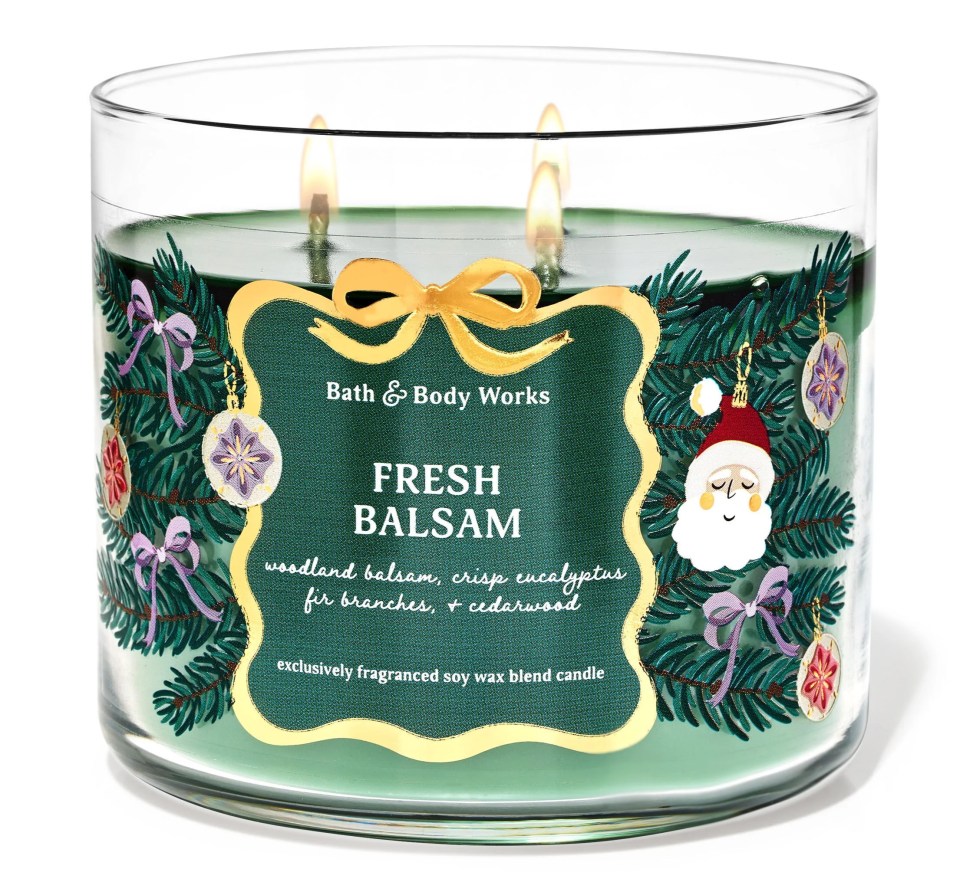 A candle with a label that reads Fresh Balsam in a white jar sitting on a table.