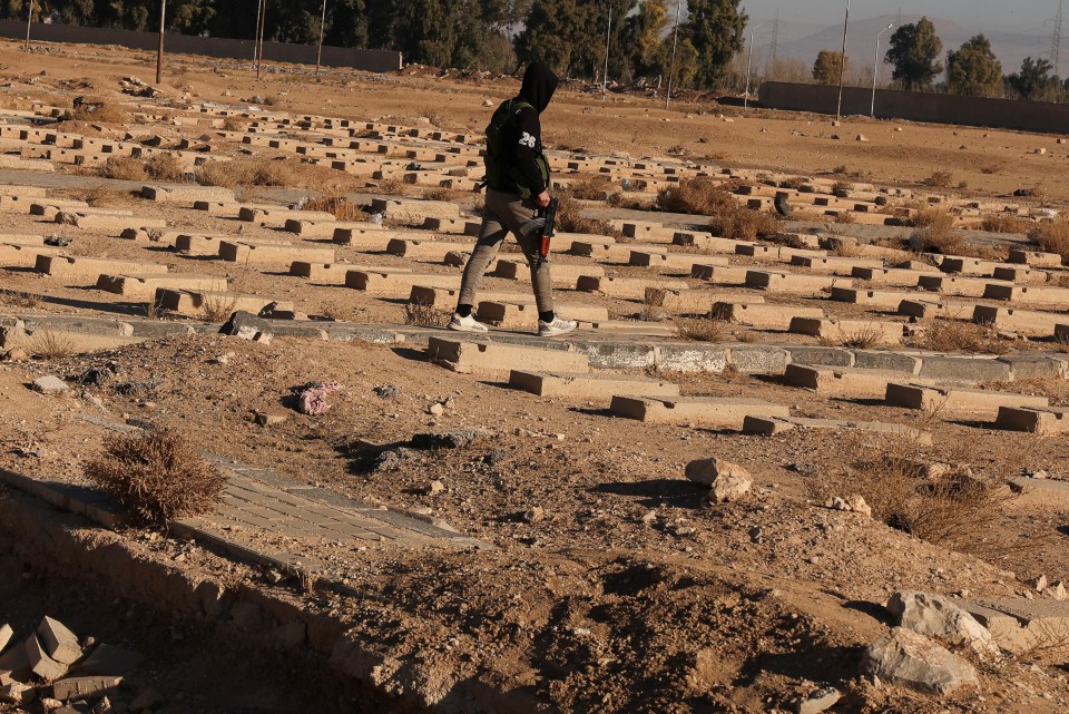 A man walks through the site of a mass grave in Najha, Syria, December 15