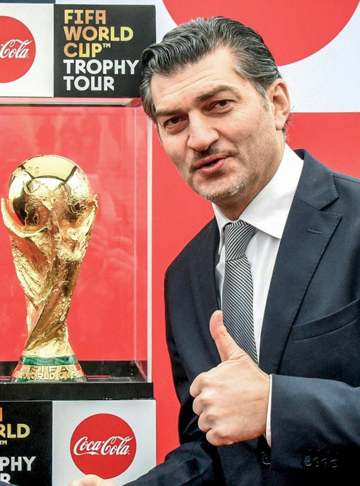 Mikheil Kavelashvili, former Georgian international football player, gives a thumbs-up next to the FIFA World Cup trophy.