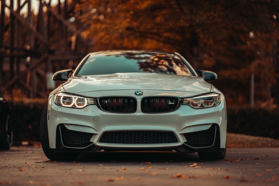 Front view of a white BMW M4 parked on a street.