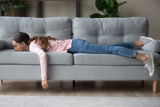 A young woman lying exhausted on a couch.