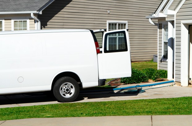 A white cleaning service van parked in a residential driveway.