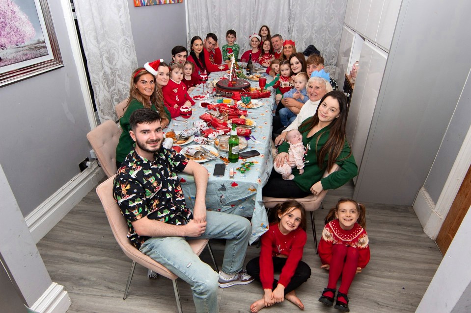 a photo of a group of people sitting around a table smiling and having a Christmas party