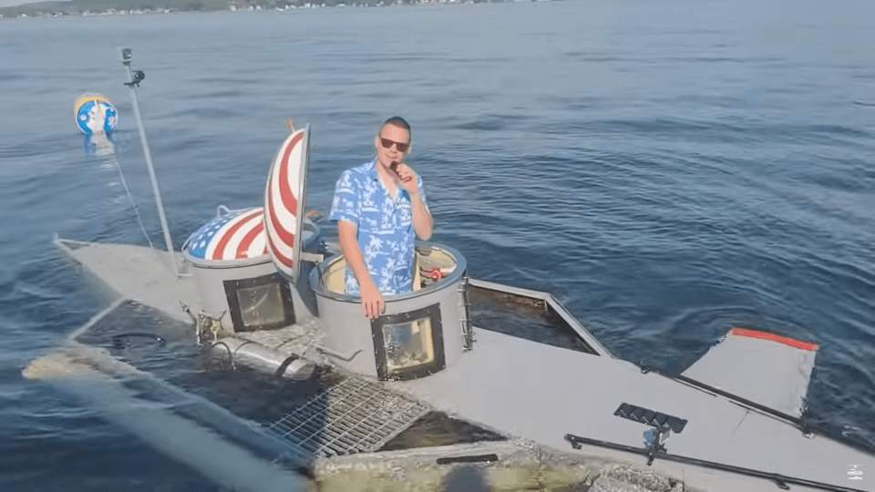 Man in a homemade submarine partially submerged in water.