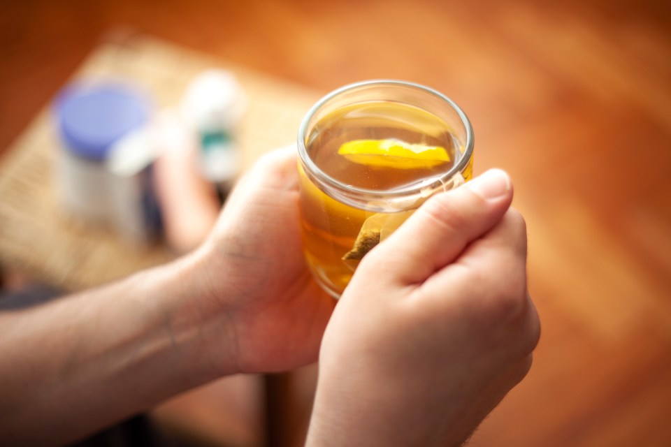 Person resting at home with a cup of tea and lemon.