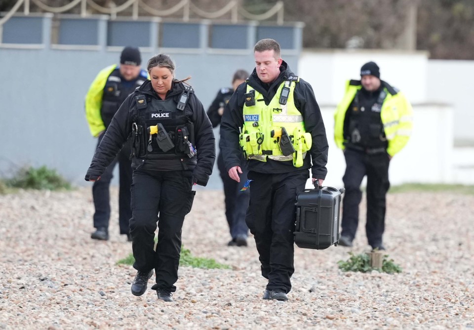 Police officers on a beach during a large-scale search.