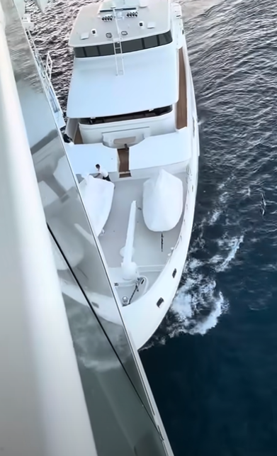 White yacht viewed from a ship's side.