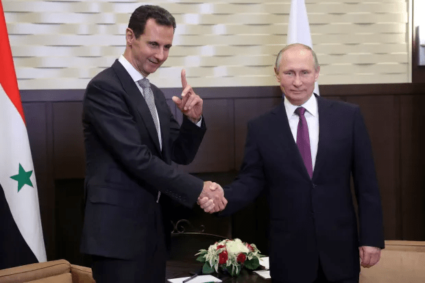 Bashar al-Assad and Vladimir Putin shaking hands.