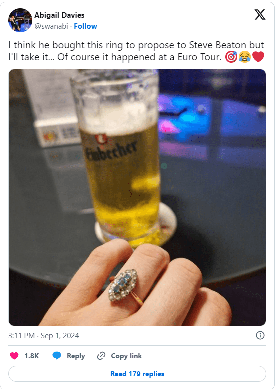 Engagement ring on a hand with a beer in the background.