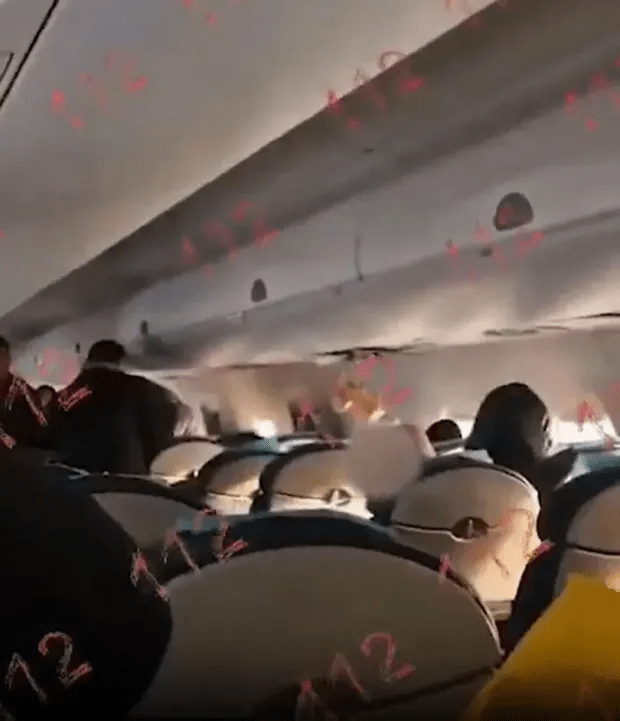 Airplane cabin with passengers during turbulence.