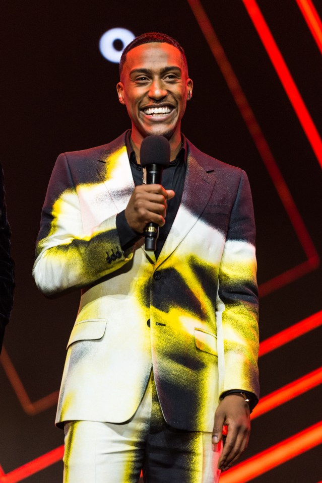 Man in a spray-painted suit holding a microphone.