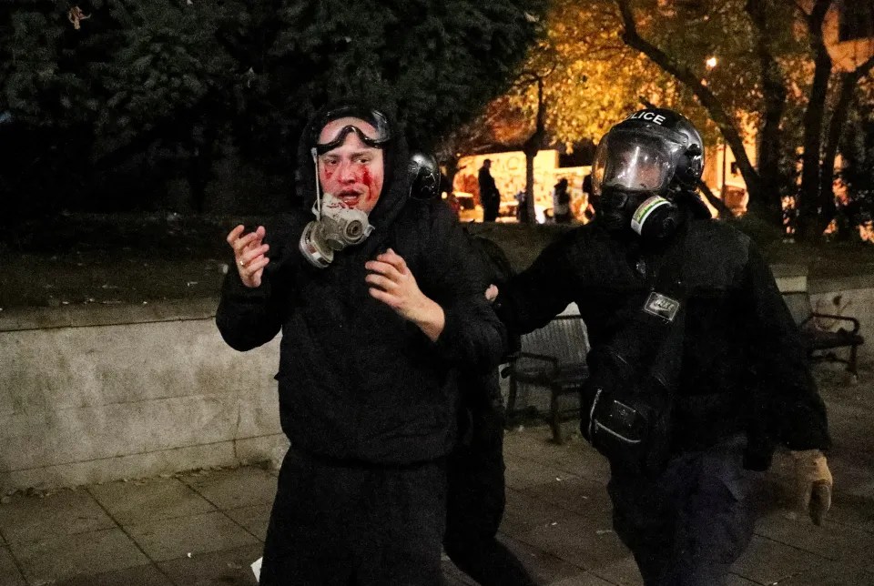 A bloodied protester being led away by police.