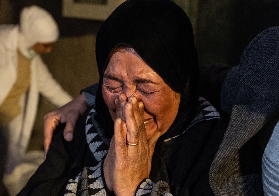 A woman cries as they searching for missing family members gather outside at Al Mujtahid Hospital to identify bodies