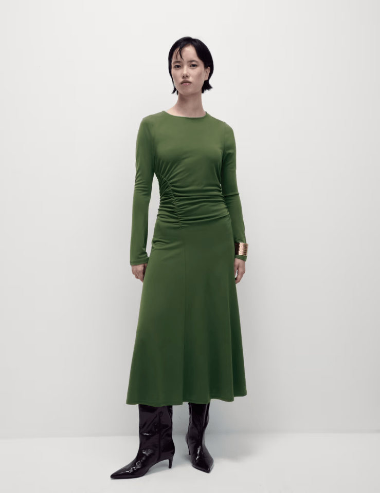 Woman in olive green midi dress and black boots.