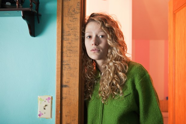 Teenage girl leaning against a doorway.