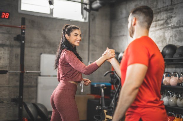 Woman and man shaking hands in a gym after a workout.