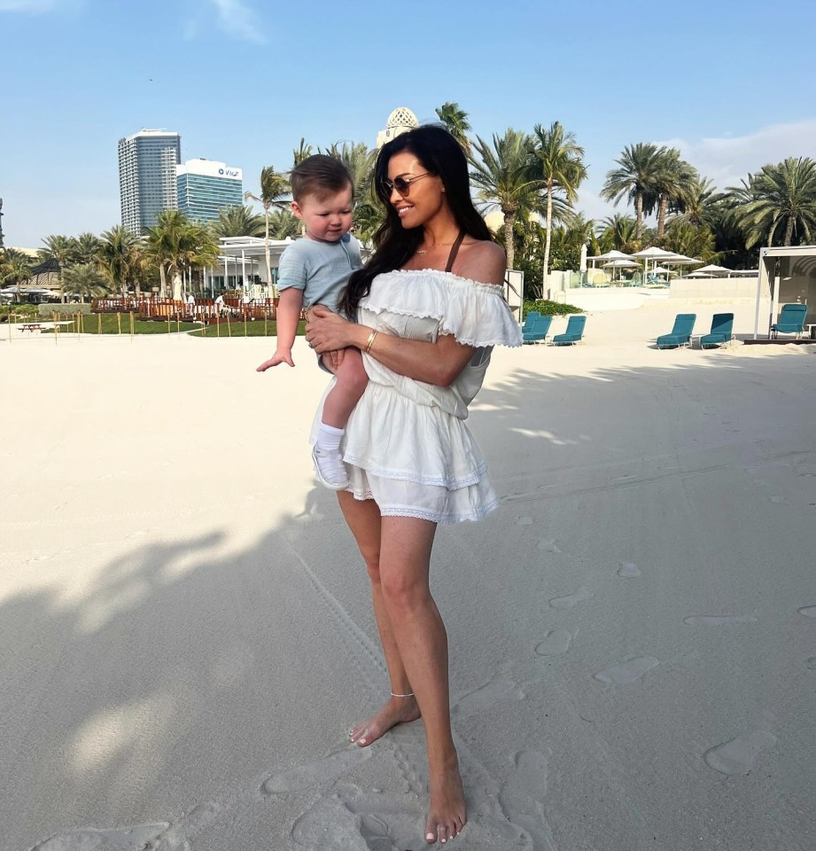 Woman holding a baby on a beach in Dubai.