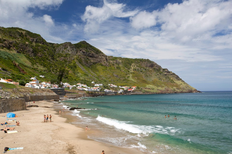 Sao Lourenco Bay beach in the Azores, with people swimming and sunbathing.