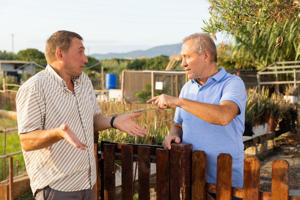 Two men arguing by a fence.