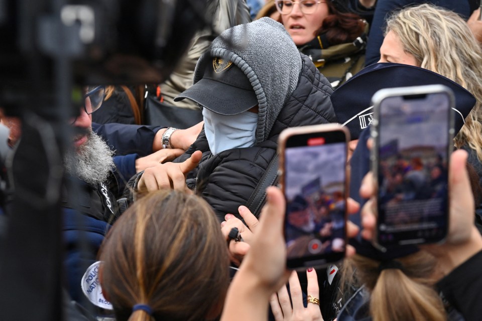 A convicted defendant in the trial given a suspended sentence pushes his way through crowds outside court