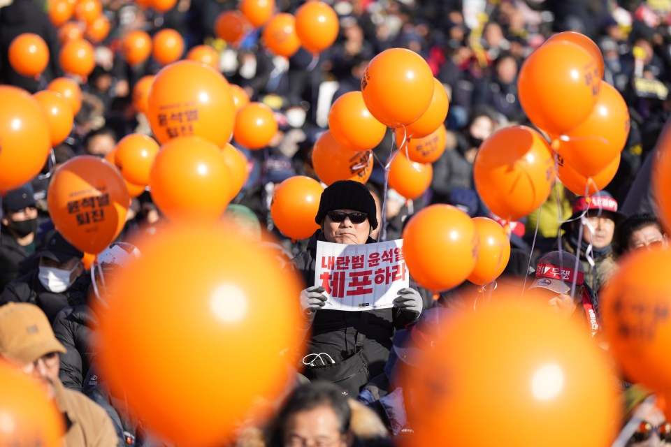 A man holds a sign reading 'Arrest Yoon Suk Yeol' during a rally on 14 December