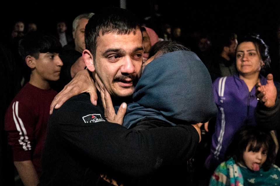 A man reacts while embraced by a woman as relatives greet former prisoners released by the Syrian Kurdish administration