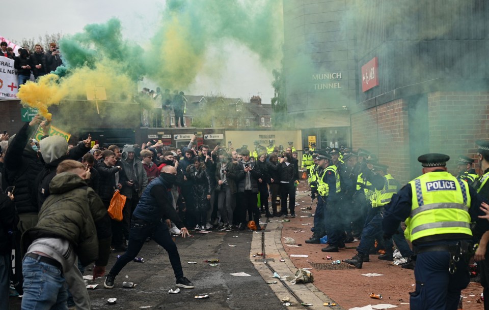 Police officers confronting protestors outside Old Trafford stadium.