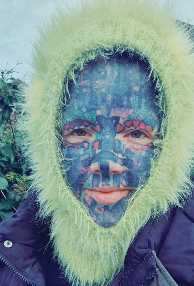 Close-up of a heavily tattooed woman wearing a lime green fluffy-collared jacket.